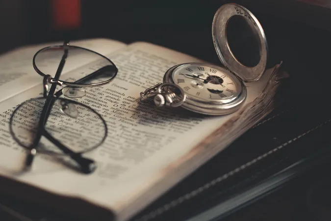 Une paire de lunettes et une montre de poche posées sur un livre ouvert.
